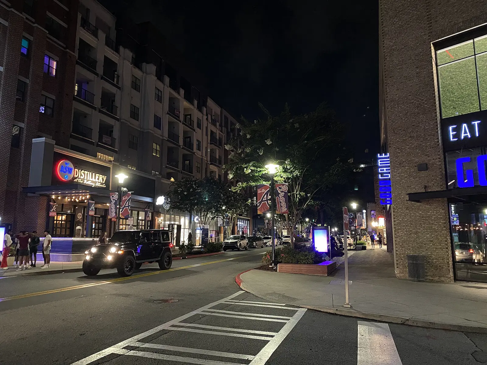 Restaurants and apartments along a street at The Battery Atlanta at night